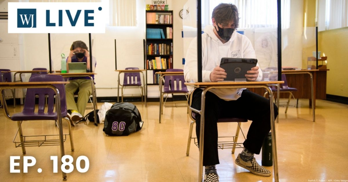 Students sitting behind barriers work on Apple iPad tablets as they return to in-person learning at St. Anthony Catholic High School during the COVID-19 pandemic on March 24 in Long Beach, California.