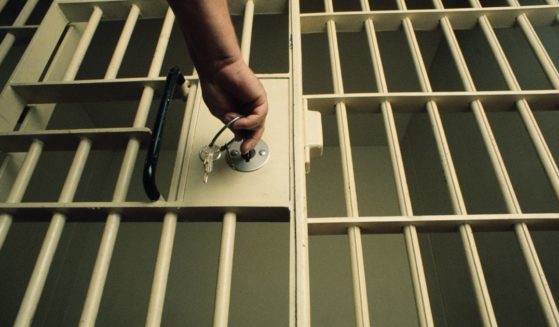 A man locks a prison cell door in the above stock image.
