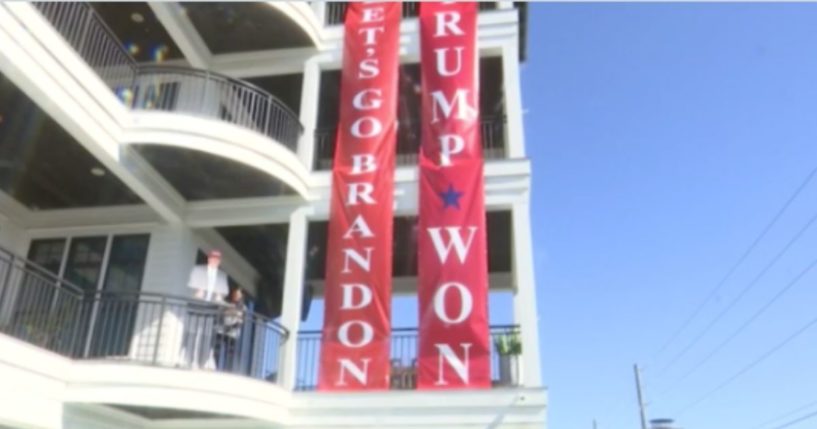 A man in Walton County, Florida, unfurls a "Let's Go Brandon" banner next to his controversial "Trump Won" banner outside his home.
