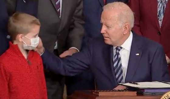 President Joe Biden caresses the face of a 7-year-old boy at the White House on Thursday.