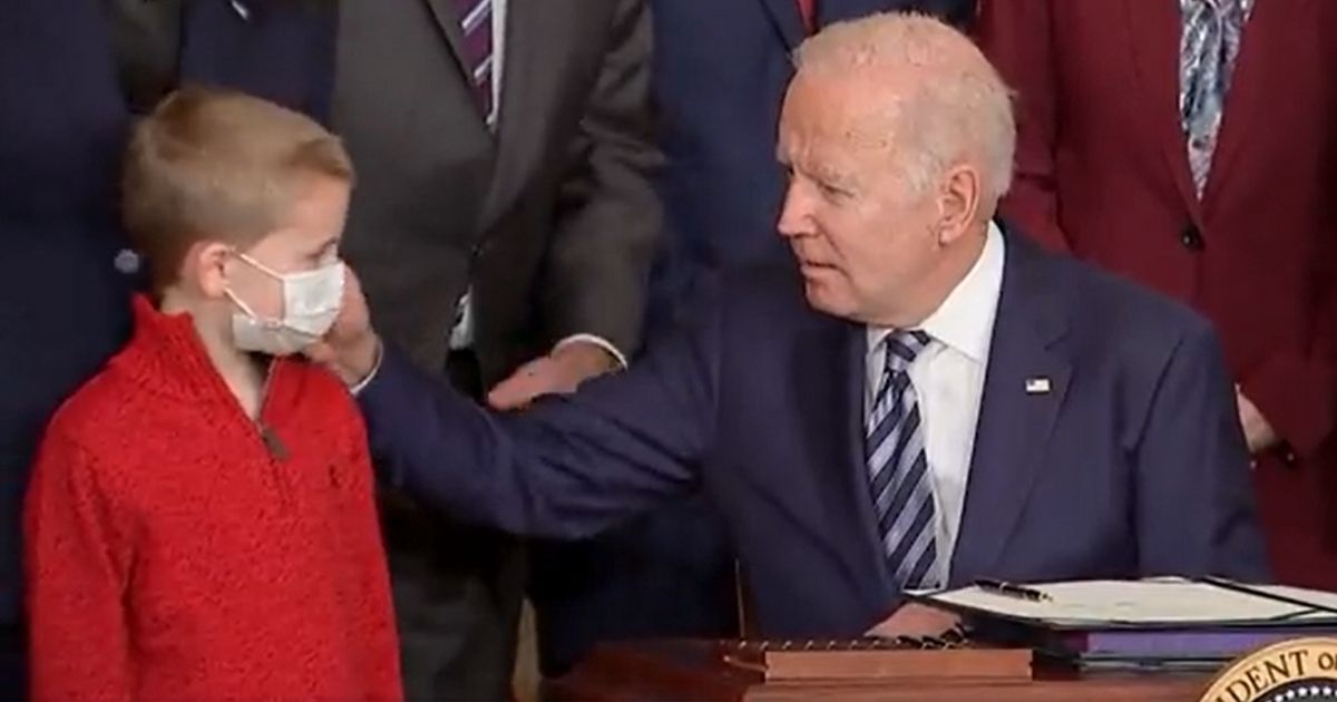 President Joe Biden caresses the face of a 7-year-old boy at the White House on Thursday.
