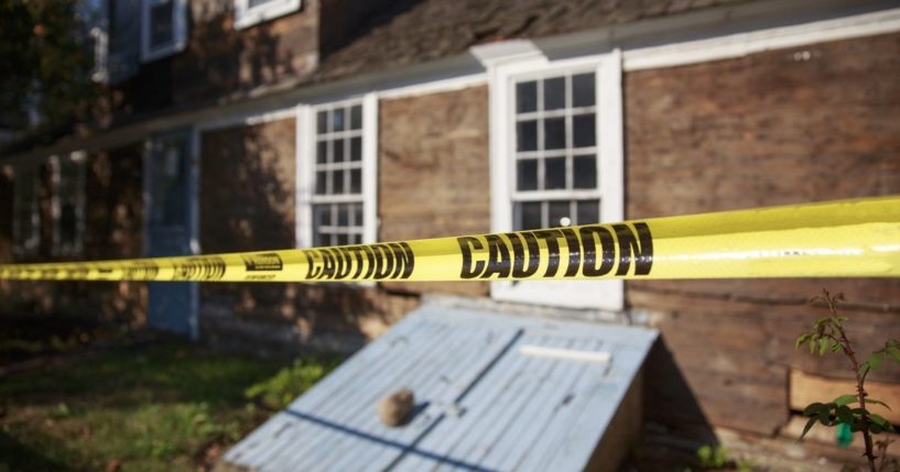 Police caution tape is seen in a backyard in the stock image above.