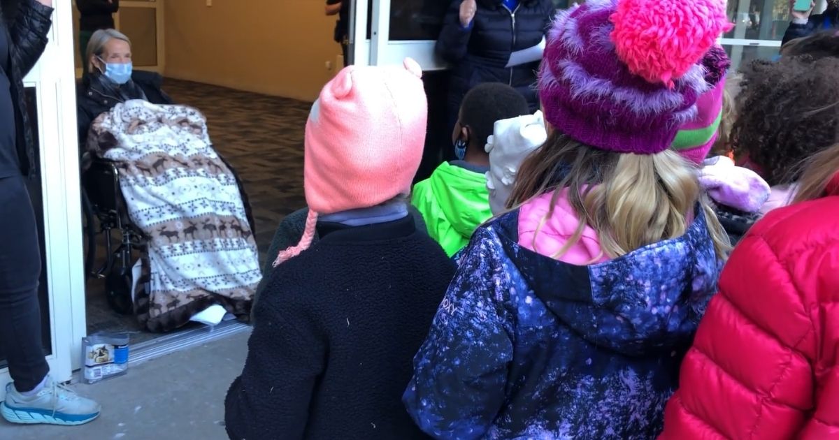 Elementary school students sing to teacher Carol Mack as she heads for hospice care.