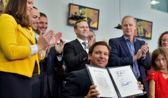 Florida Gov. Ron DeSantis holds up a newly signed bill protecting employees and their families from coronavirus vaccine and mask mandates during a news conference Nov. 18 in Brandon, Florida.
