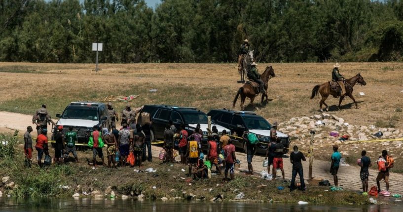 Border patrol officers detain a group of migrants after they crossed the Rio Grande near Del Rio, Texas, on Sept. 19.