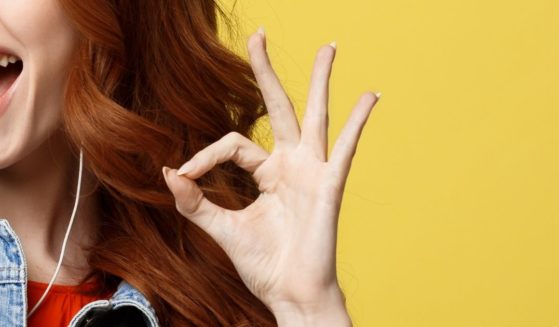 A woman makes an 'OK' symbol with her hand.