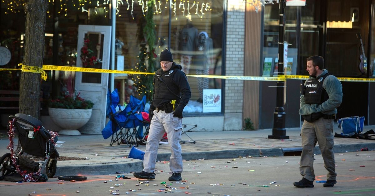 Police officers canvas debris left after a man driving an SUV plowed into the Christmas parade on Main Street in downtown Waukesha, Wisconsin, on Sunday