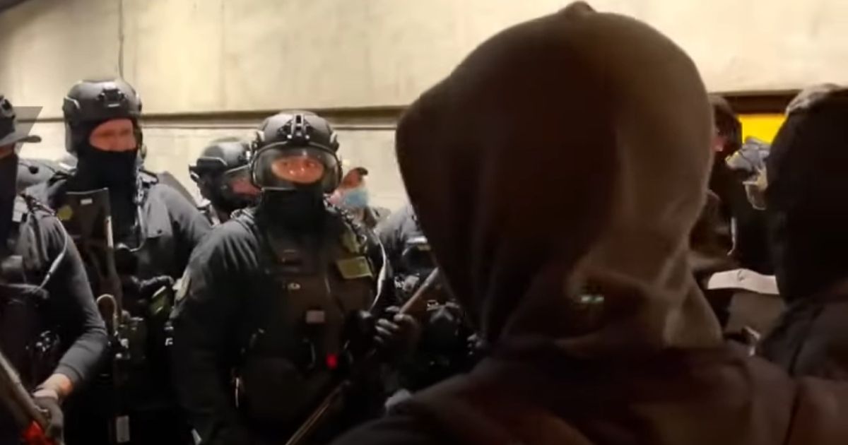 Portland, Oregon, police officers are confronted by protesters as the door of the Multnomah County Jail garage opens during a demonstration Friday.