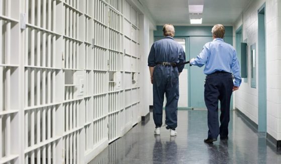 This stock image shows a prison guard leading an inmate down a hallway. In Colorado, officials moved to drop the term "sex offender" as it is too debilitating to sexual abusers.