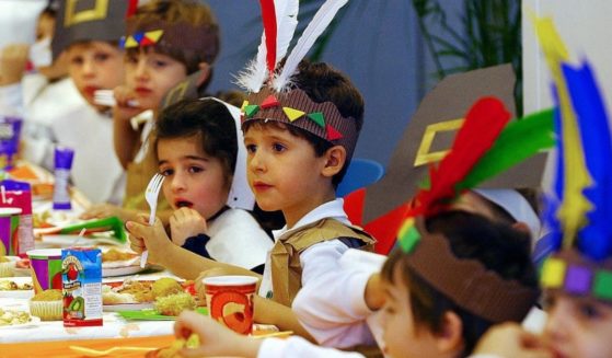Kindergarten students wearing costumes depicting Native Americans and Pilgrims eat lunch during Thanksgiving eve festivities at the Lycee Francais in New York on Nov. 26, 2003.
