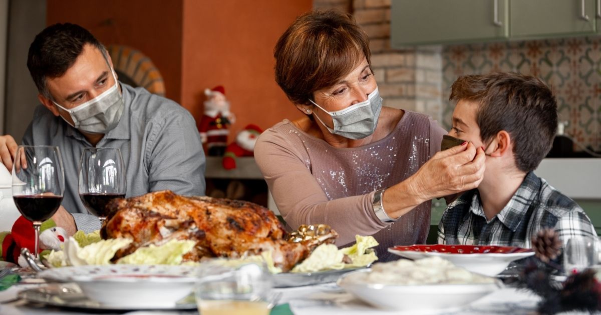 A family wears face masks while sitting down for Thanksgiving dinner.