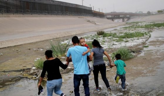 Migrants hold hands as they cross the border between the U.S. and Mexico at the Rio Grande river, on their way to enter El Paso, Texas, on May 20, 2019, as taken from Ciudad Juarez, Mexico.