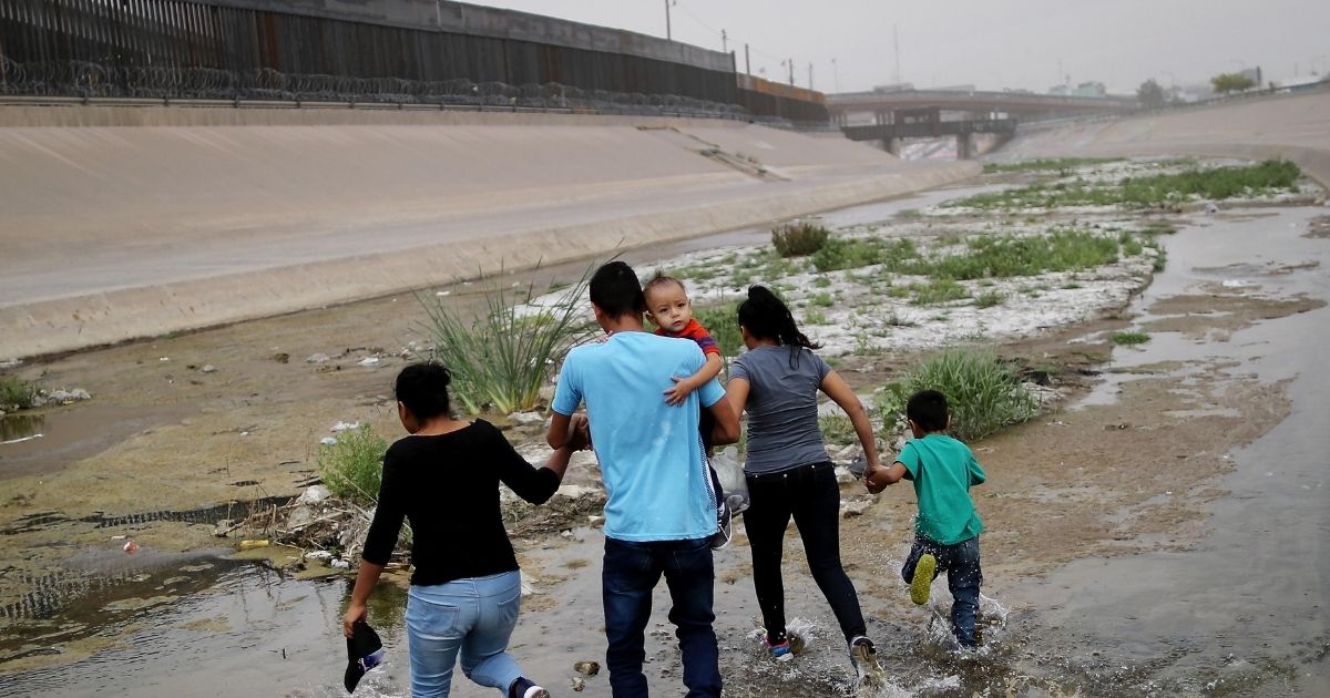 Migrants hold hands as they cross the border between the U.S. and Mexico at the Rio Grande river, on their way to enter El Paso, Texas, on May 20, 2019, as taken from Ciudad Juarez, Mexico.