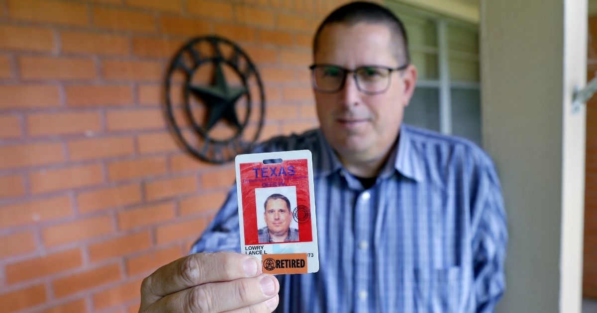 Lance Lowry, a recently retired corrections officer with the Texas State Penitentiary, holds his ID badge on the front porch of his home in Huntsville, Texas, on Wednesday.