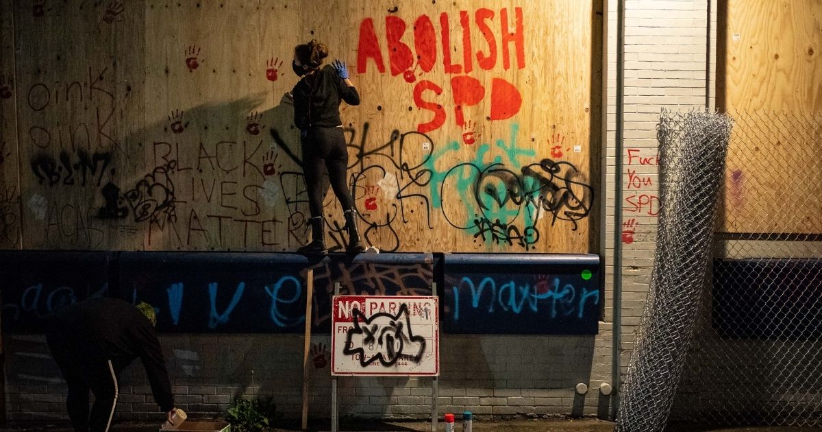 Vandals paint the exterior of the Seattle Police Department's East Precinct in June 2020 during protests that created an "autonomous zone" in the city.