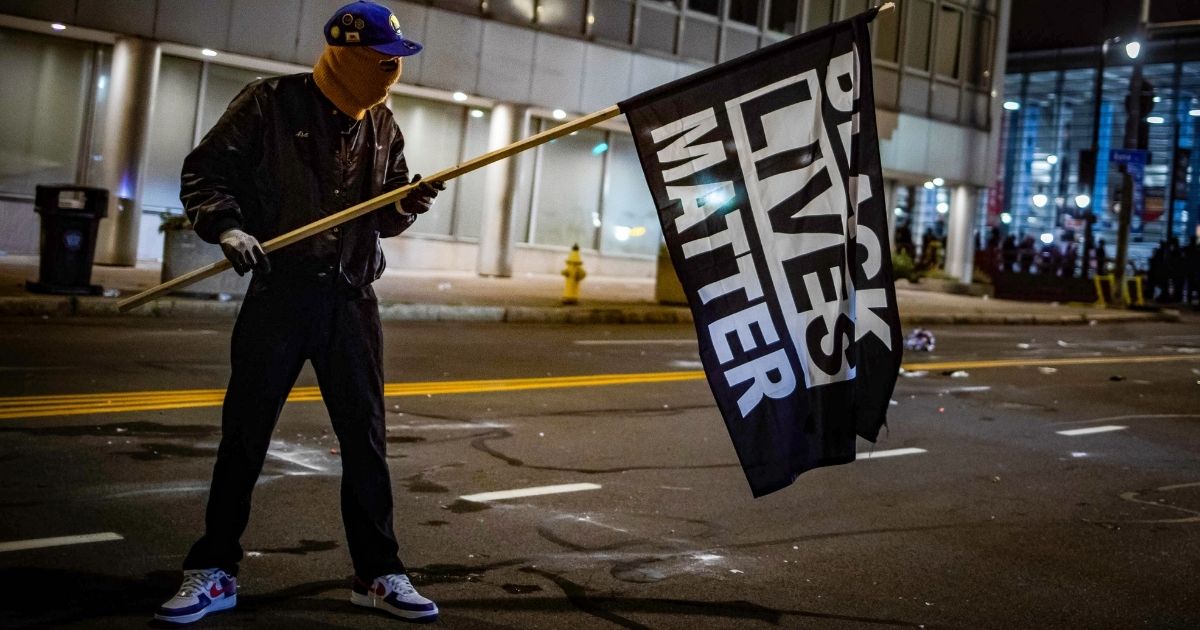 A rioter wearing a Black Panther jacket holds a "Black Lives Matter" flag in Rochester, New York, on Sept. 5, 2020.