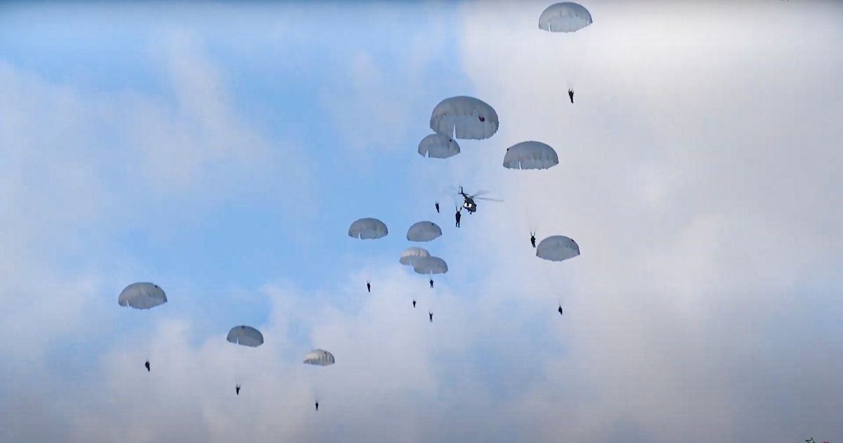 In this photo taken from video released by the Belarusian Defense Ministry Press Service on Nov. 12, 2021, Russian paratroopers jump from military helicopters during a military exercise near the Belarus-Poland border.