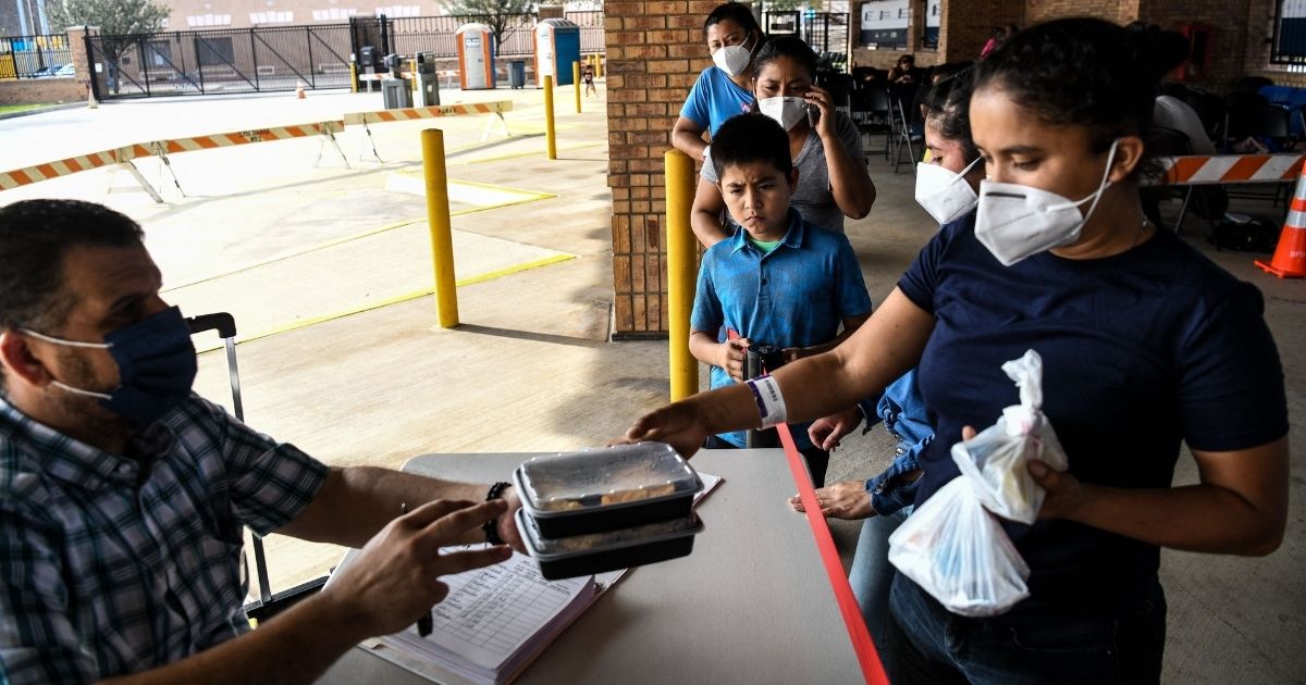 Illegal immigrants from Central America get food while awaiting results of COVID-19 tests near Brownsville, Texas, in March.