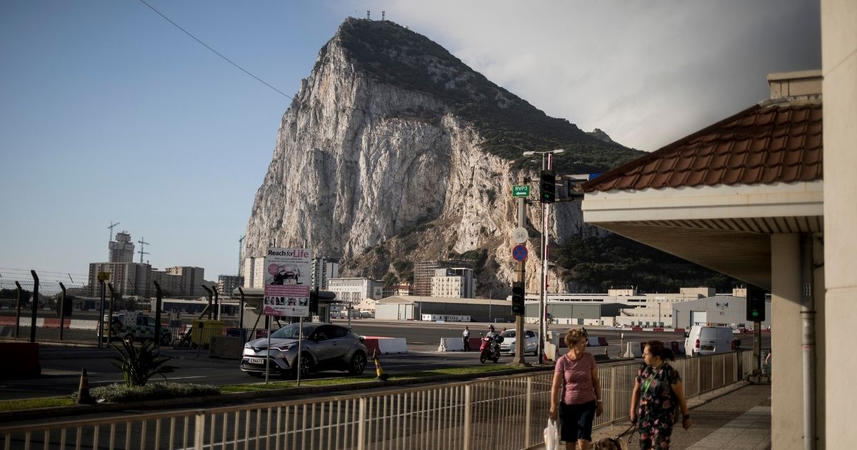 Backdropped by the Rock of Gibraltar, people cross the airport runway in Gibraltar, a high-vaccination-rate British territory on Spain's southern coast, on June, 24, 2021.
