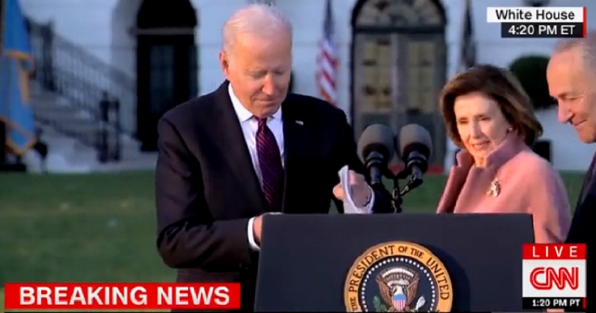 President Joe Biden searches for his mask at a podium outside the White House on Monday.