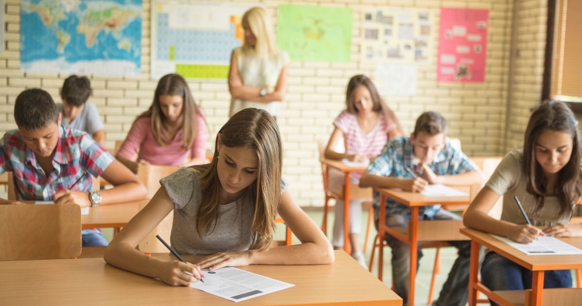 A teacher observes her students in a classroom in this stock image.