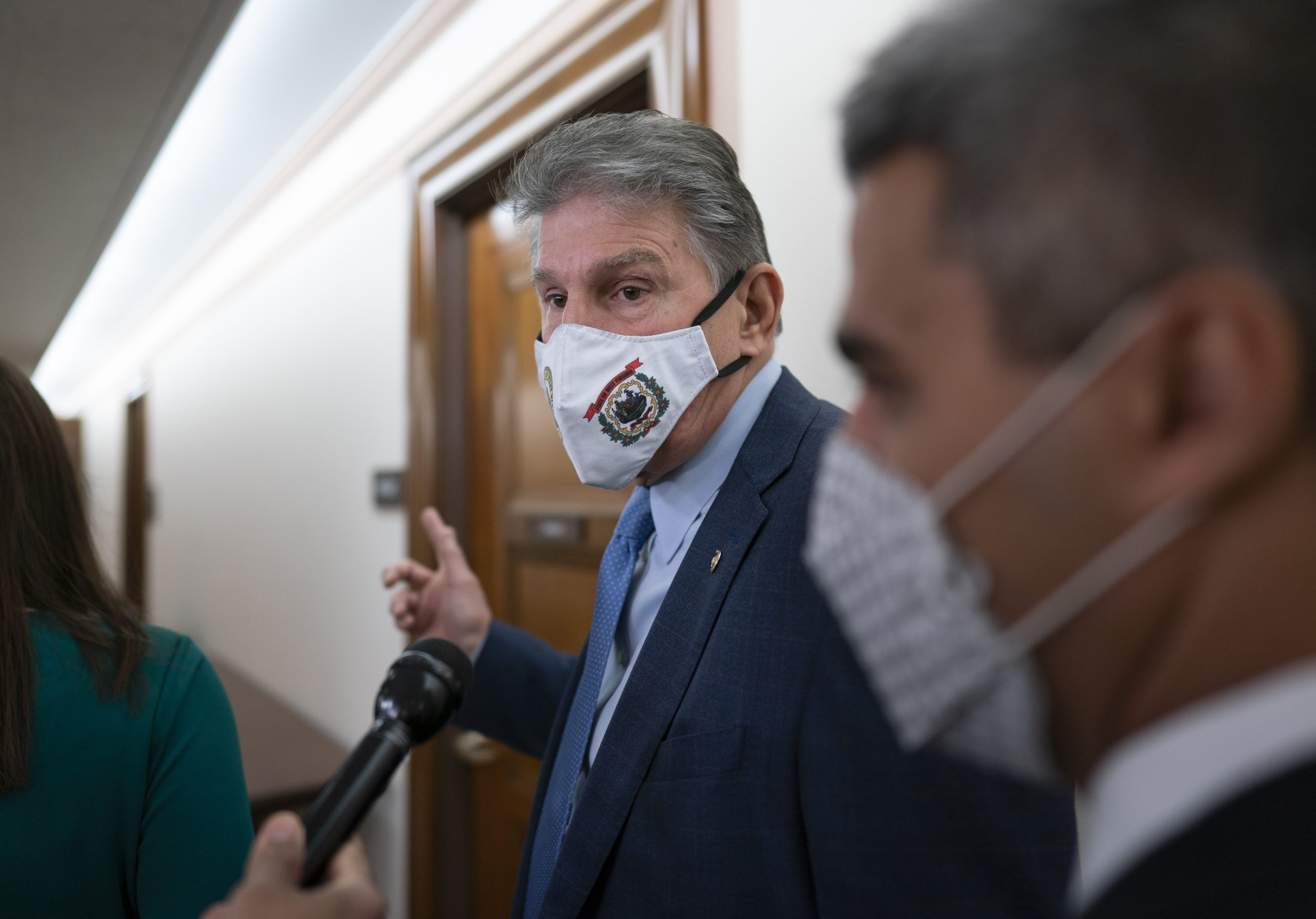 Democratic Sen. Joe Manchin of West Virginia, a key vote on President Joe Biden's domestic spending agenda, tells reporters he's late for a hearing and can't talk at the Capitol on Dec. 2.