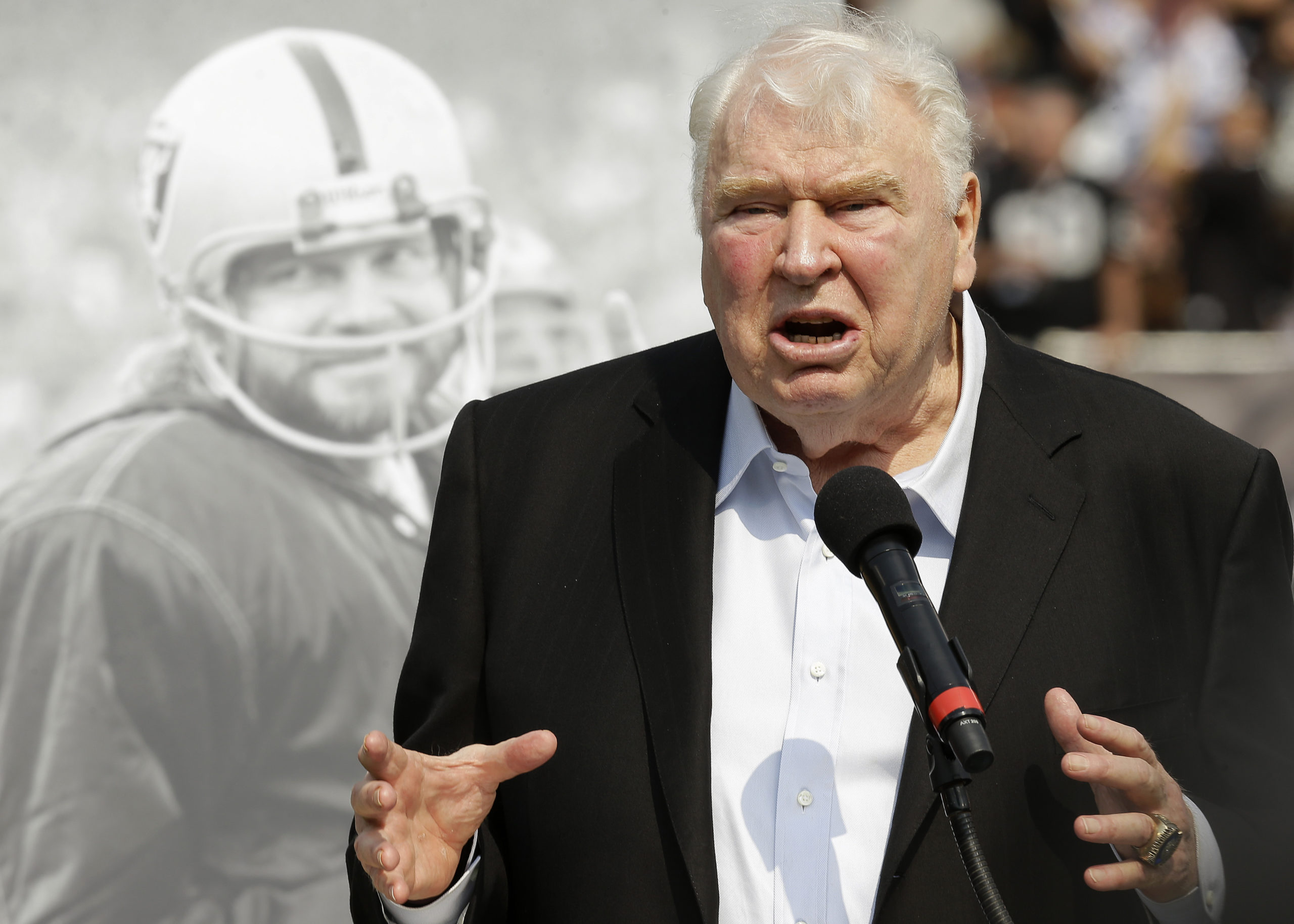 Former Oakland Raiders head coach John Madden speaks about former quarterback Ken Stabler, pictured at rear, at a ceremony honoring Stabler during halftime of an NFL football game between the Raiders and the Cincinnati Bengals in Oakland, California, on Sept. 13, 2015.
