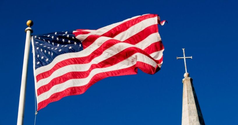 An American flag and a church steeple are seen in this stock image.