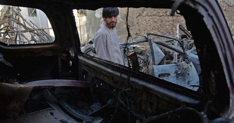 A relative of Zemerai Ahmadi is seen through the wreckage of a vehicle that was destroyed in a U.S. drone strike in Kabul, Afghanistan, on Sept. 18.
