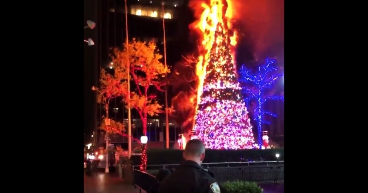 The Christmas tree standing outside the Fox News building is set on fire late Tuesday night.