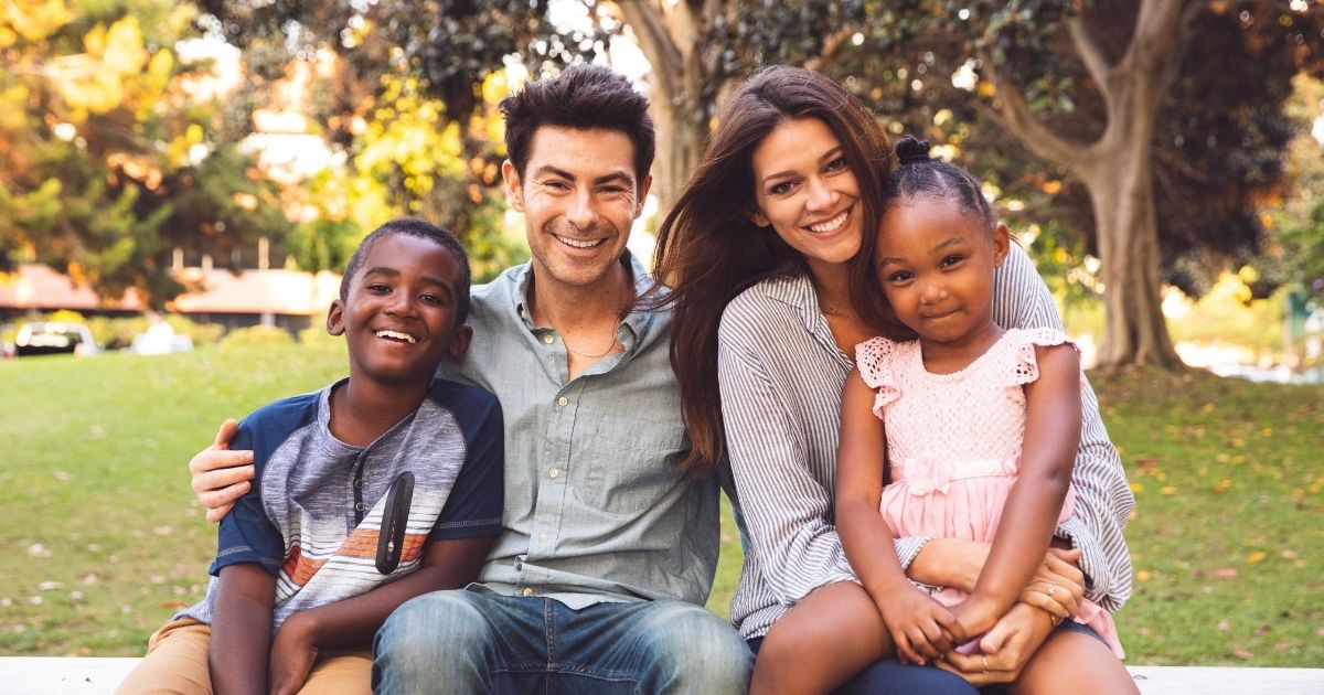 This stock photo shows a multiracial family with their adoptive children.