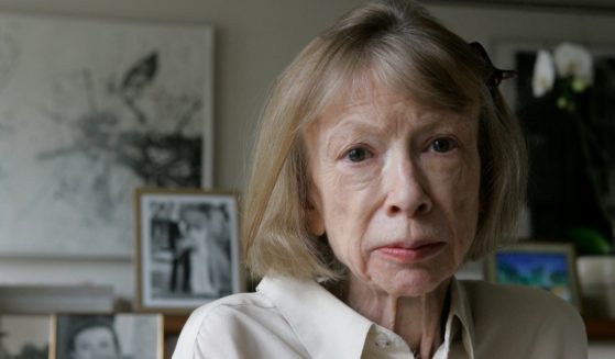 Author Joan Didion sits in front of a photo of herself holding her daughter, Quintana Roo, and another picture of her daughter's wedding, in her New York apartment on Sept. 26, 2005.