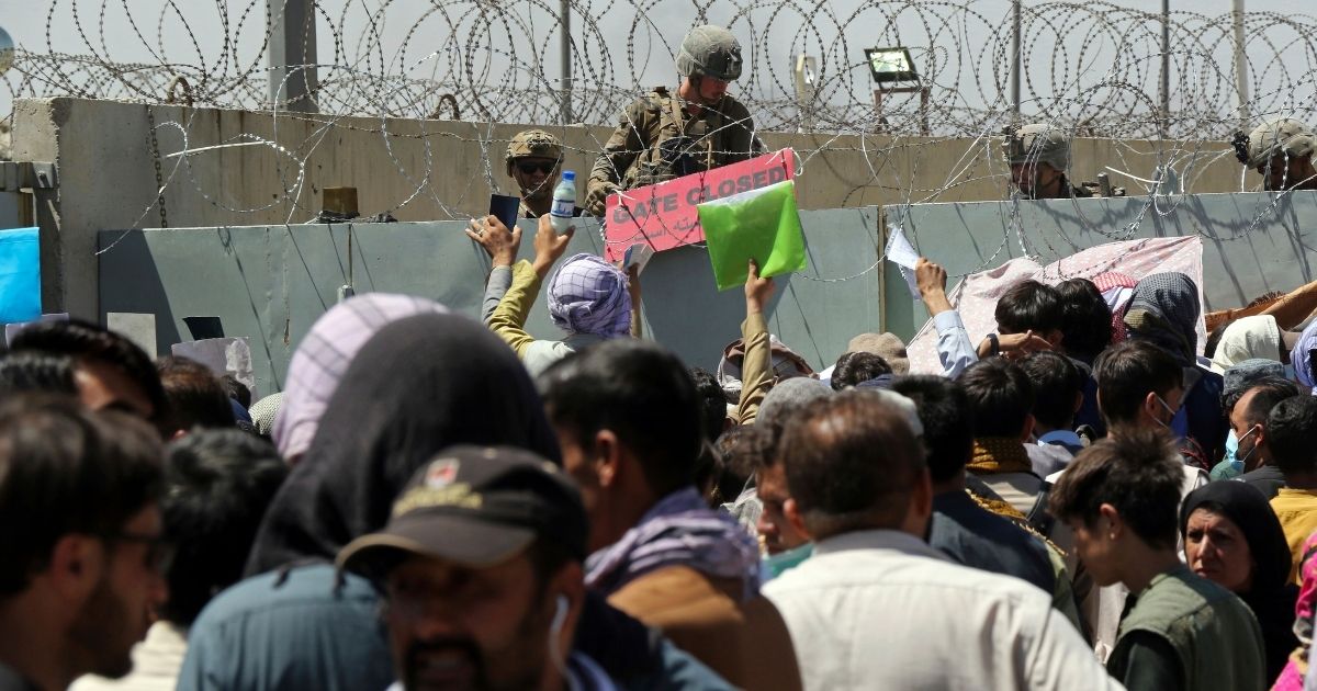 Hundreds of people gather at Hamid Karzai International Airport, in Kabul, Afghanistan, on Aug. 26, in hope of being able to board a plane to leave the country after the Taliban takeover; however, a U.S. soldier indicates in this photo the gate is closed, and no one will be able to use the entrance to get through in hopes of leaving.
