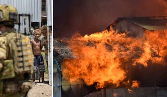 At left, young boys watch Australian Army Cpl. Aaron Woodham as he patrols Saturday. At right, a building burns in the capital city of Honiara, Solomon Islands, Friday, Nov. 26. Several nations are sending troops to help with violence that has erupted over the Pacific nation''s increasing links with China.