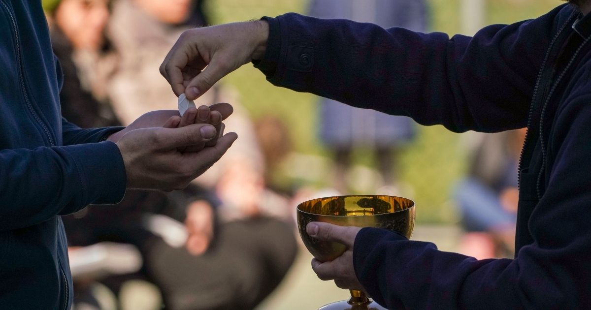 A priest serves communion in a file photo from March 2020. A Michigan diocese has attracted criticism for advising transgender individuals that they must repent in order to participate in sacraments.