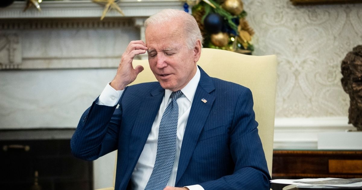 President Joe Biden scratches his head in the Oval Office.