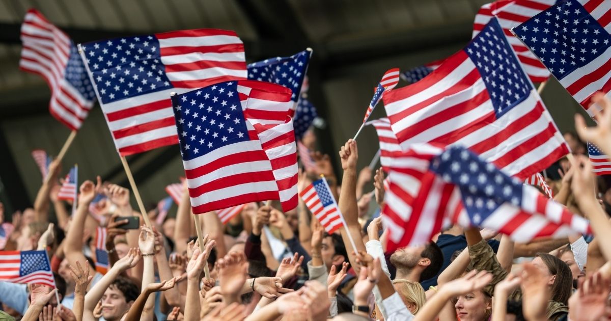A crowd waving American flags is seen in the above stock image.