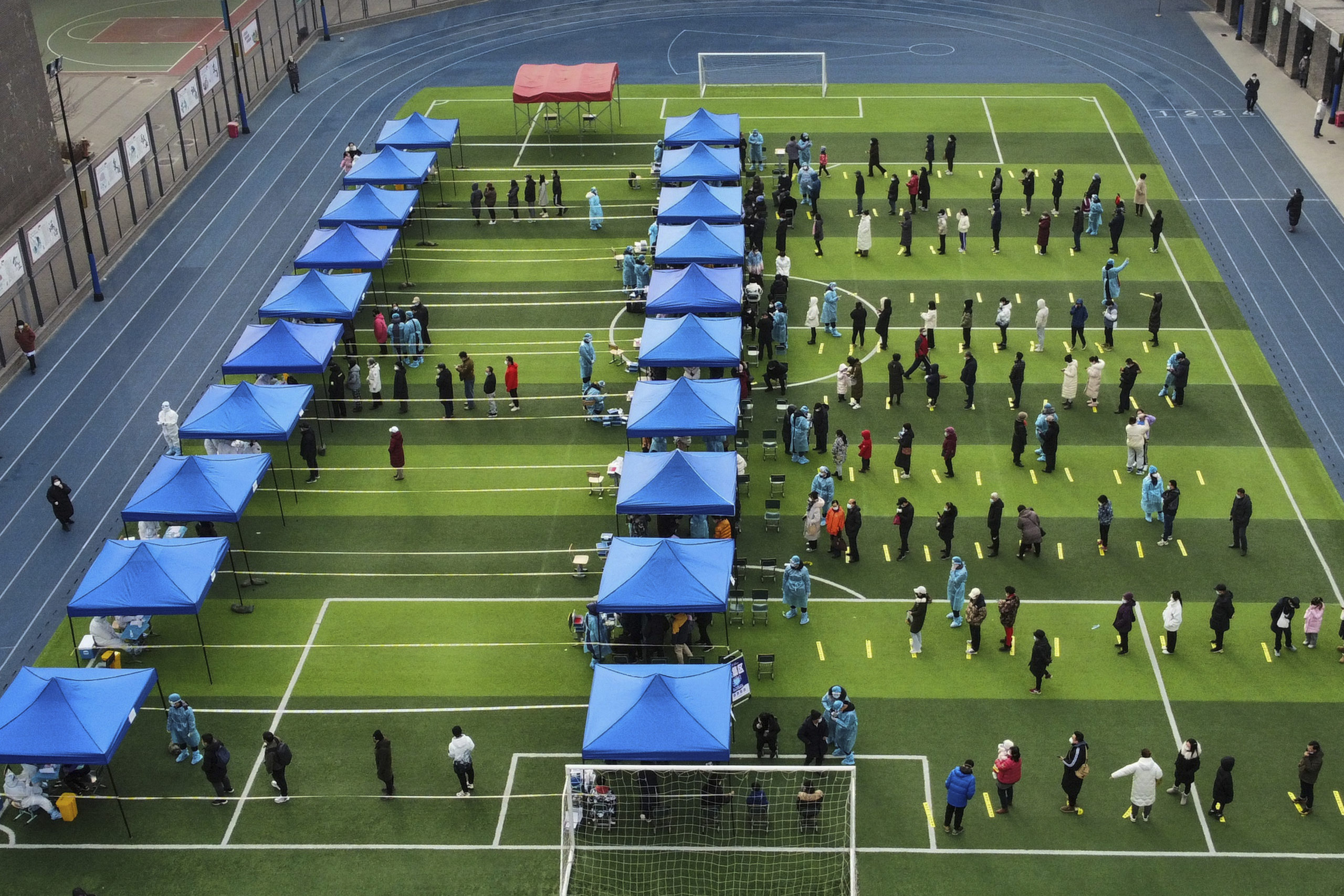 Residents line up on a football field for a COVID test during a mass testing in north China's Tianjin municipality on Sunday.