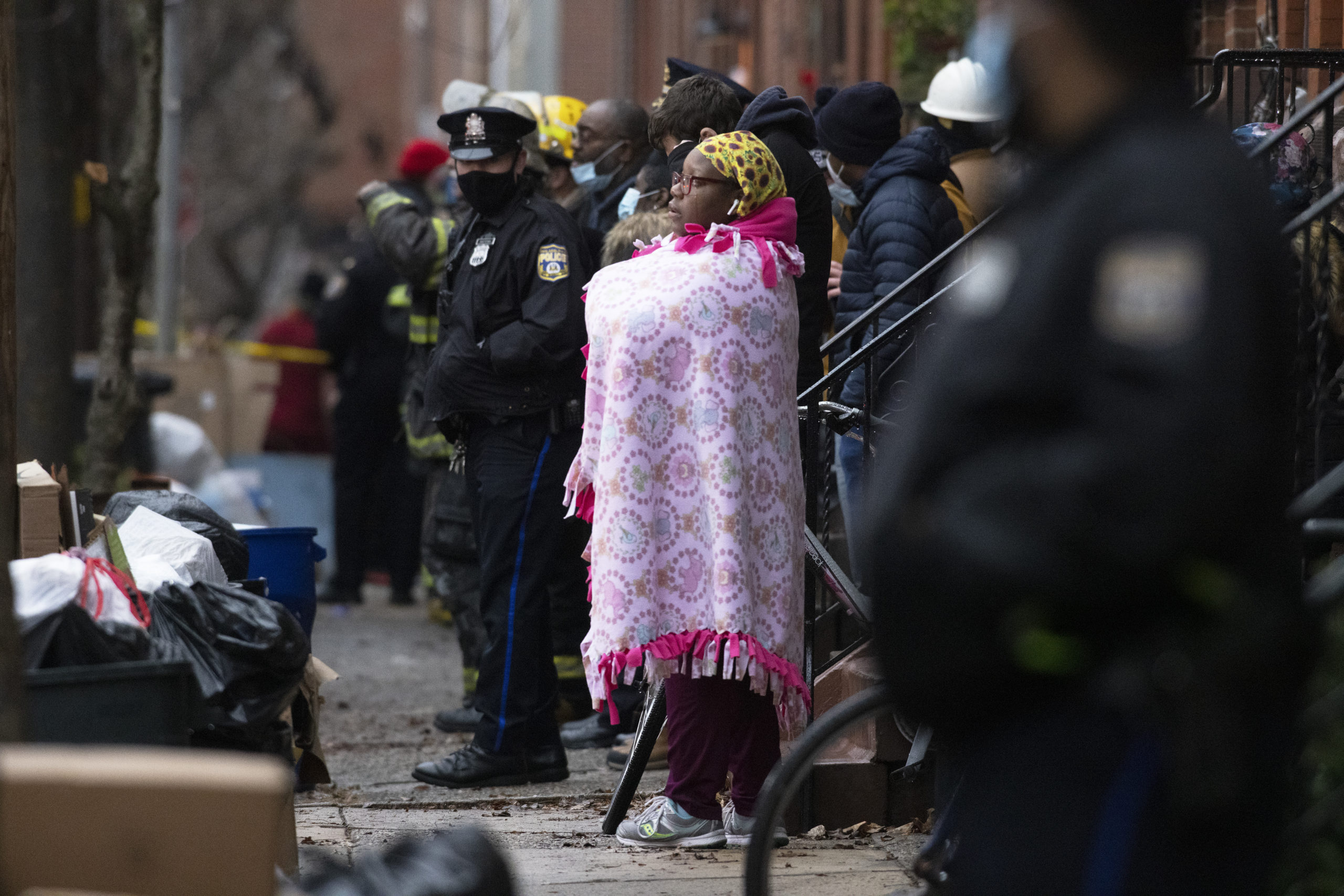 Bystanders watch as the Philadelphia fire department works at the scene of a deadly row house fire in Philadelphia Wednesday.