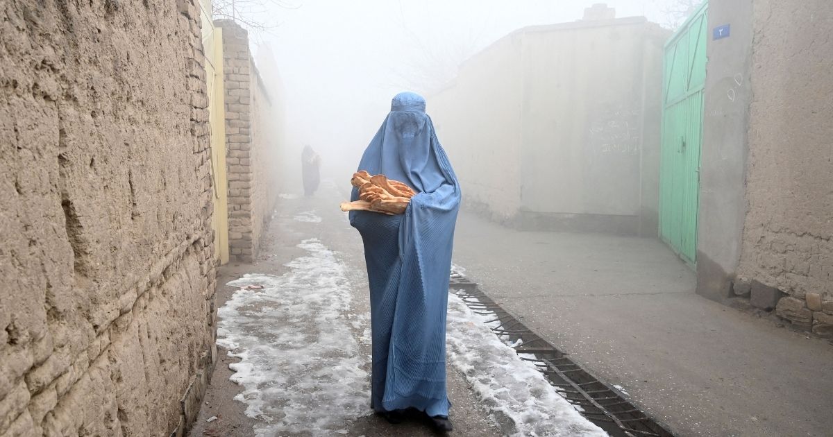 A woman wearing a burqa walks along a road toward her home after receiving free bread distributed as part of the 'Save Afghans From Hunger' campaign in Kabul on Jan.18. The effort launched last week was organized by a university professor in Kabul, according to a report by the Tulsa World. Afghanistan is in the grip of a humanitarian catastrophe, compounded by the Taliban takeover in August, when Western countries froze international aid and access to assets held abroad. The Save Afghans from Hunger campaign at fundly.com has raised more than $45,000 to provide necessities such as flour, rice, oil, beans, chickpeas, milk and sometimes green tea and sugar