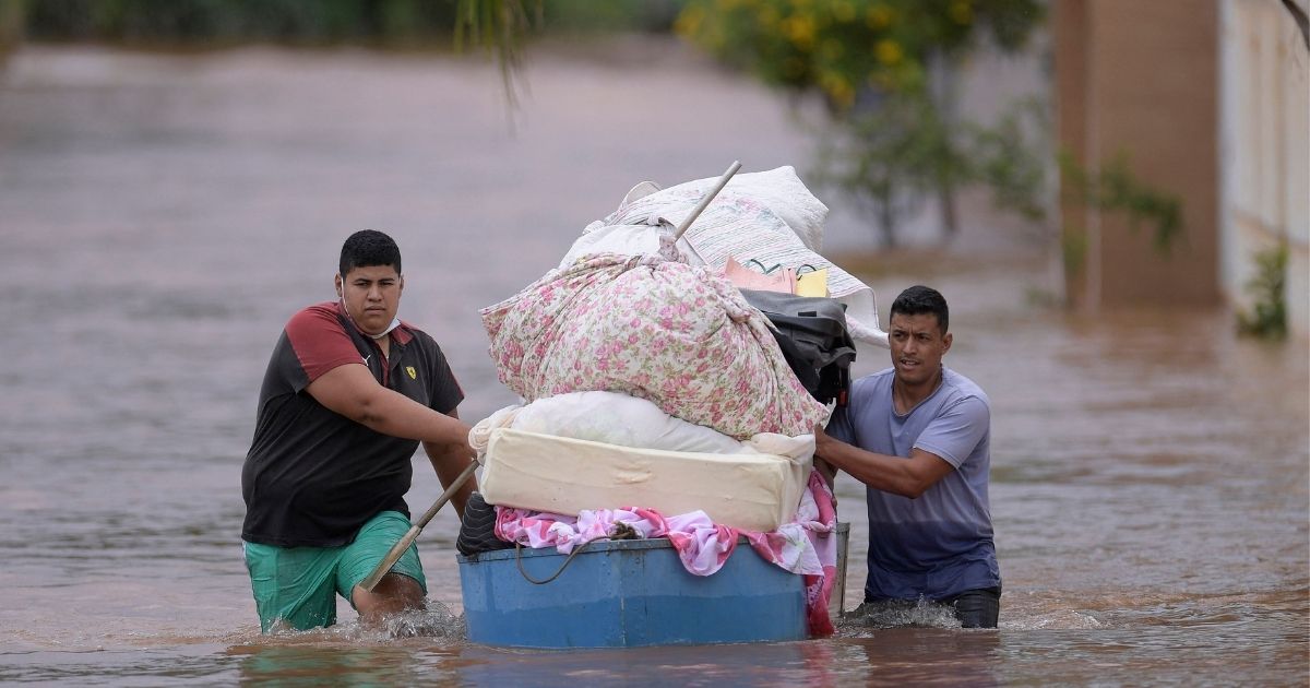 People wade through the water as they remove belongings from their homes in the flooded Brazilian municipality of Juatuba, located in the state of Minas Gerais, on Monday, Jan. 10. Extremely heavy rain has fallen in recent days in the southeastern part of the country.