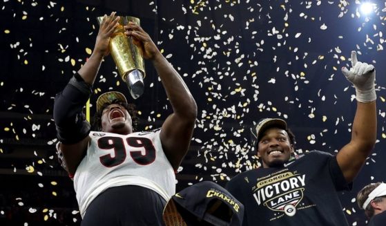 Georgia defensive tackle Jordan Davis celebrates with the national championship trophy after the Bulldogs defeated the Alabama Crimson Tide 33-18 at Lucas Oil Stadium in Indianapolis on Monday night.