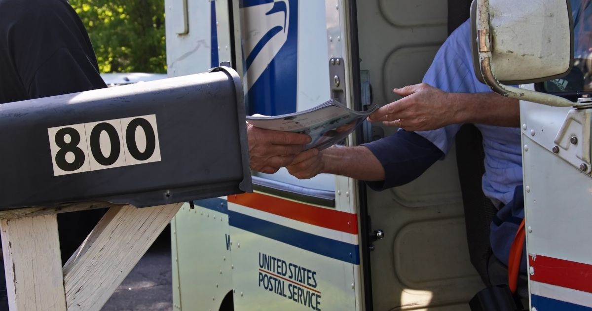 A postal worker hands a man his mail in Cromwell, Connecticut, on May 18, 2019.