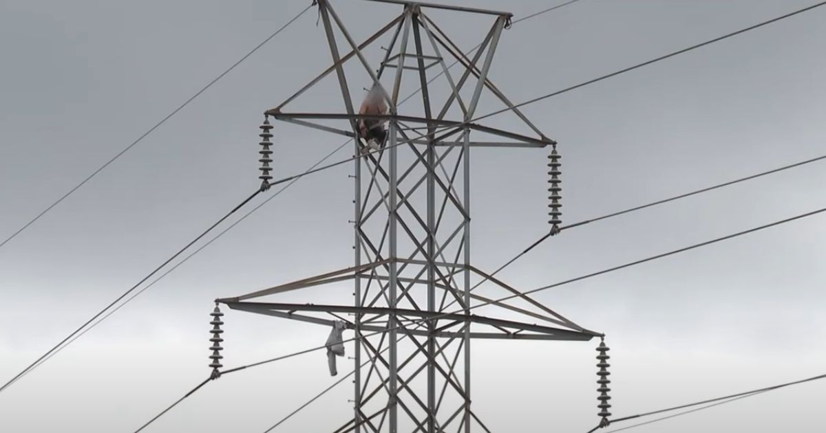 A man is perched atop an electrical tower in Charlotte, North Carolina, on Sunday.