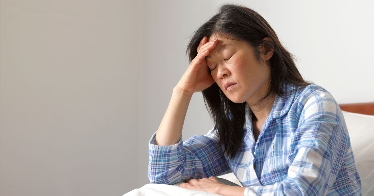 This stock image shows a woman feeling sick and holding her head in bed. As the omicron variant spreads, doctors are warning that people should be on the watch for a new symptom: night sweats.