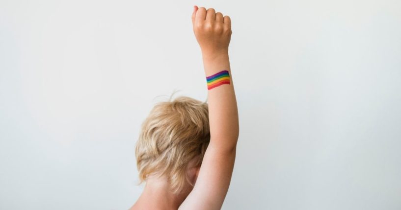 This stock image shows a young boy raising his arm, which has a rainbow flag painted on it. On Jan. 7, a Canadian law banning the so-called 