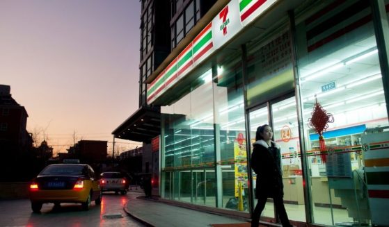 A woman walks past a 7-Eleven convenience store in Beijing. The Texas-based chain has more than 71,000 stores around the world.