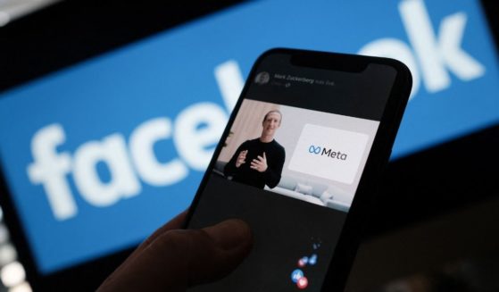 In this illustration photo taken in Los Angeles on Oct. 28, 2021, a person watches on a smartphone as Facebook CEO Mark Zuckerberg unveils the Meta logo. Zuckerberg announced the parent company's name is being changed to 'Meta' to represent a future beyond its social network.