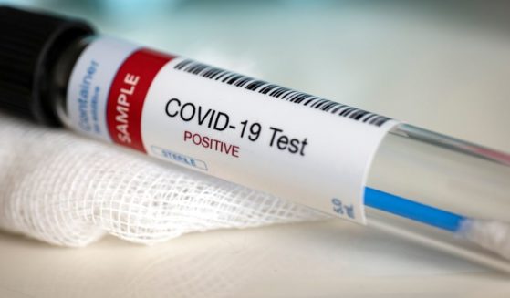 A tube containing a coronavirus test swab is labeled "positive."