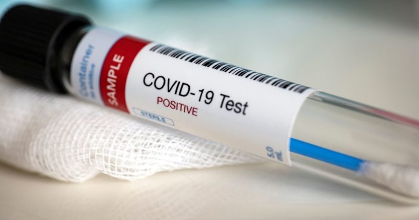 A tube containing a coronavirus test swab is labeled "positive."
